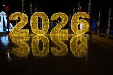 Glowing 2026 numbers illuminated in a dark winter city. Festive New Year decoration creating a bright holiday atmosphere at night.
