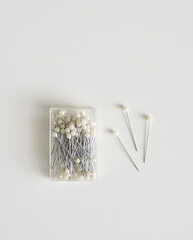 Pearl Head Sewing Pins in Clear Container on White Minimalist Background with Copy Space