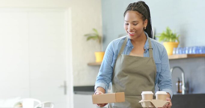 Woman server emerging from counter in cafe delivering coffee tray and food box to customer