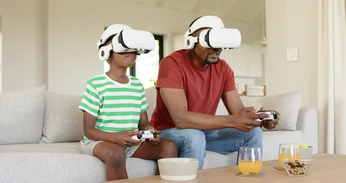 Upon donning white VR headsets African American father and son tapping controllers bonding at home