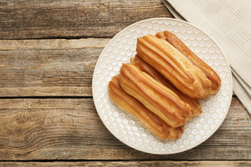 Fresh tasty eclairs on wooden table, top view. Space for text