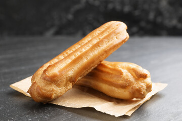 Tasty eclairs on black table, closeup. Delicious dessert