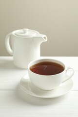 Hot tea in cup and teapot on white wooden table