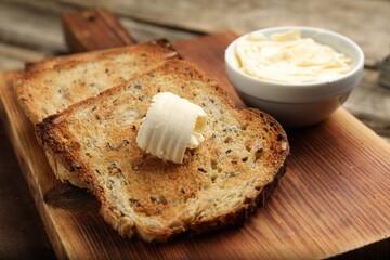 Slices of toasted bread with butter on wooden table, closeup