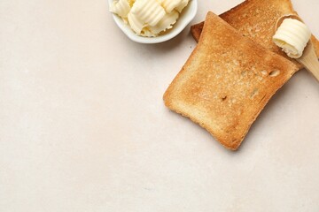 Slices of toasted bread and butter on beige table, flat lay. Space for text