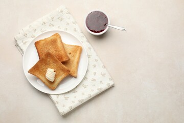 Slices of toasted bread, butter and jam on beige table, flat lay. Space for text