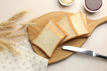 Slices of toast bread, butter and jam on beige table, flat lay