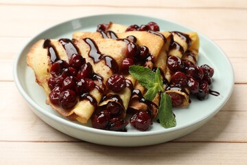 Tasty crepes with cherries, chocolate and mint on white wooden table, closeup