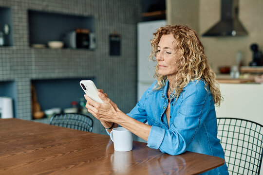 Portrait of a mature senior woman or a businesswoman working from home having a meeting online, home office, or a student learning, or mature woman having a phone call, holding a mobile phone, smartp - Powered by Adobe