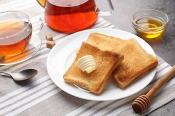 Fresh toasted bread slices with butter, honey and tea on table