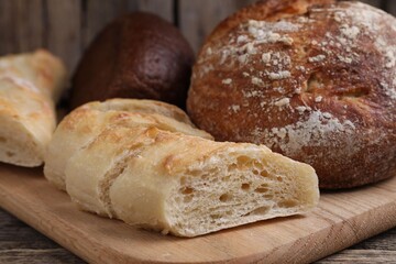 Different types of bread on wooden table, closeup