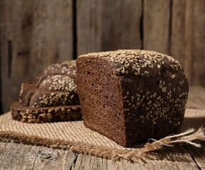 Delicious fresh rye bread with sesame seeds on wooden table, closeup