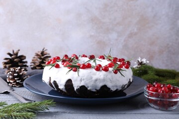 Tasty Christmas cake with cranberries, rosemary and festive decor on gray wooden table, closeup
