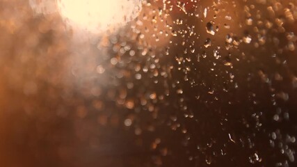 Camera pulling back along glass with raindrops in warm romantic rainy atmosphere - Powered by Adobe