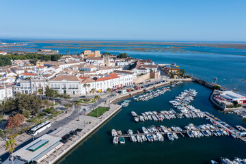 Visitors explore the dock in Faro, Algarve under clear skies. Boats are lined up in the water near the historic old town and Ria Formosa area