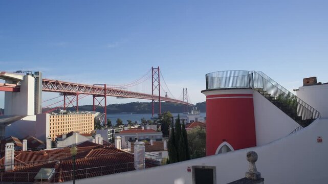 View of the 25 de Abril bridge and Tagus river from Santo Amaro chapel terrace area in Lisbon, Portugal on a clear sunny day in Autumn. Shot on a cinema camera with vintage lens