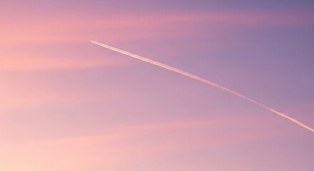 Airplane contrail at sunset in pink and purple sky