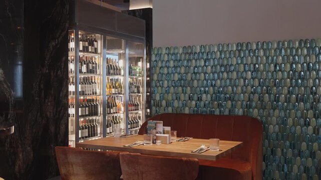 Customer browses through illuminated bottles in fridge before making relaxed beverage selection