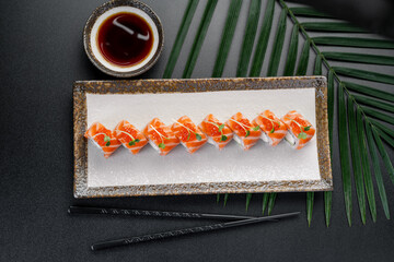 Salmon Maki Rolls with Cream Cheese and Roe Topping. A row of vibrant salmon rolls filled with cream cheese and cucumber is crowned with bright red caviar. © Анна Терелюк