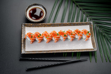 Salmon Maki Rolls with Cream Cheese and Roe Topping. A row of vibrant salmon rolls filled with cream cheese and cucumber is crowned with bright red caviar. © Анна Терелюк