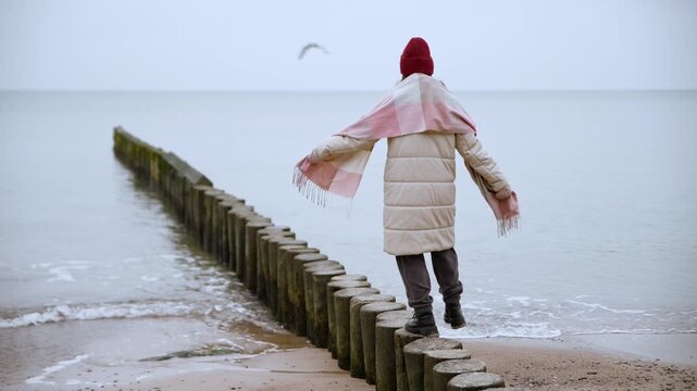 Baltic Sea portrait of person balancing on wooden groynes in calm overcast weather