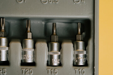 Tool set containing various screwdriver bits arranged in a storage case on a yellow background