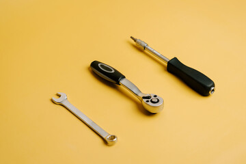 Tools are placed on a yellow surface ready for repair work in a workshop