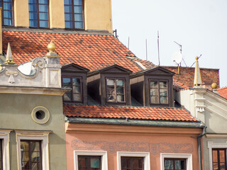 Part of a historic residential facade with dormer windows set in a red tiled roof, typical of Warsaw Old Town architecture.