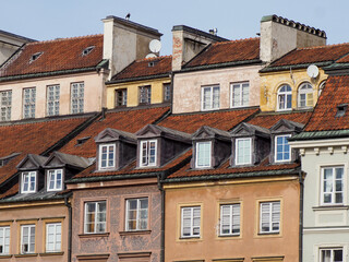 Fototapeta premium Panoramic view of beautifully restored townhouses with colorful facades and distinctive sloping red roofs in Warsaw's Old Town.