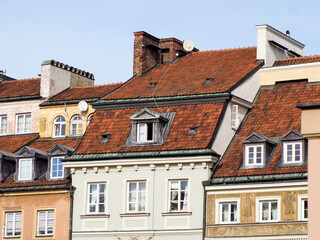 Fototapeta premium Picturesque panorama of colorful facades and steep red tiled roofs of historic townhouses in Warsaw Old Town against a blue sky.