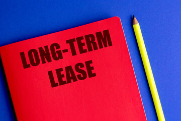Text long-term lease written on red notebook with yellow pencil on blue background