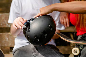 Person adjusts helmet for another person at a skate park during the day