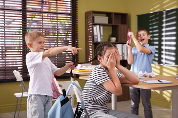 Girl getting bullied by her classmates in school, selective focus