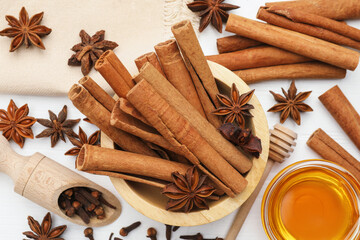 Different spices (anise, cinnamon, cloves) and honey for mulled wine on white table, flat lay