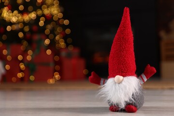 Obraz premium Funny Christmas gnome on floor in decorated room. Space for text