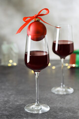 Glasses of red wine, bauble and other Christmas decor on grey table