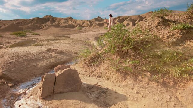 Depiction of Jesus in ancient clothes walking alone on a dusty desert path. Christian and spiritual concept. Slow motion footage