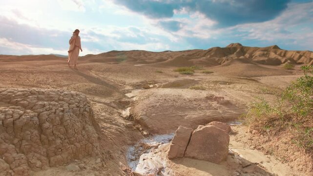 Cinematic shot of a lone walker with a staff moving across windswept desert hills and cracked earth. Evocative visual of ancient travel, isolation, and spiritual journeying. Christian concept