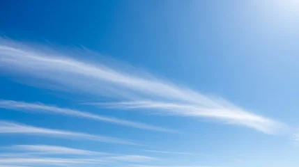 Wispy cirrus clouds streaking across a bright blue sky © Saieem