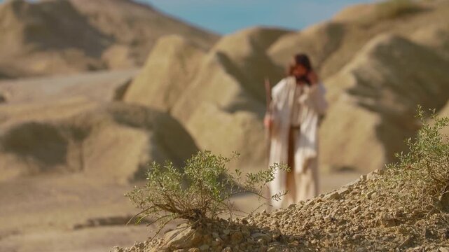 A Traveler in ancient-style clothing stepping across a dusty desert path. Christian and spiritual concept. Slow motion shot