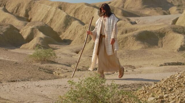 A Traveler in ancient-style clothing stepping across a dusty desert path. Christian and spiritual concept