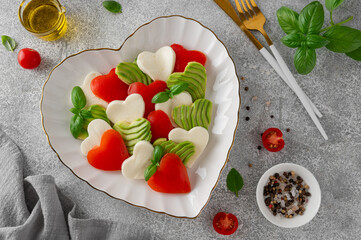 Heart-shaped caprese salad with mozzarella, tomatoes, avocado and basil. A salad for Valentine's Day or Mother's Day. Top view, copy space.