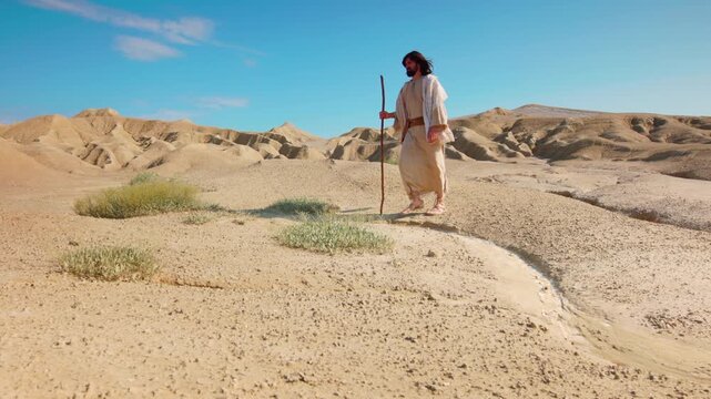 Solitary Traveler walking through vast desert. Christian and spiritual concept. Slow motion shot