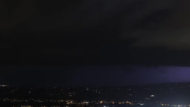breve timelapse di un grande e potente temporale estivo e notturno, con lampi e fulmini, in transito sopra ad un'area urbana tra pianura e collina, in Friuli Venezia Giulia, in Italia