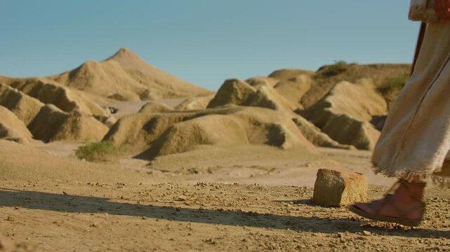 Traditional sandals and robes moving forward across rugged desert soil. Christian and spiritual concept. Slow motion Shot