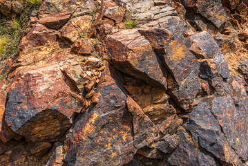 Close-up of a weathered metamorphic rock showing distinct foliation, fractures, and iron oxide staining with visible mineral oxidation patterns suggesting prolonged exposure to weathering processes.