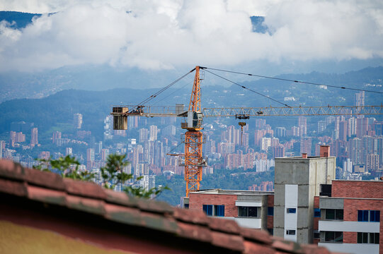 High-angle aerial view of the densely populated city of Medell&iacute;n, Colombia, sprawling across the Aburr&aacute; Valley. Urban buildings cover the surrounding hills, with the central airport runway clearly 
