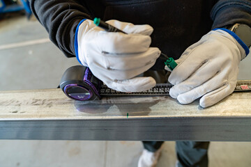 Worker hands measuring metal beam marking construction material