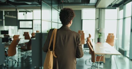 Poised woman surveys open plan professional setting confidently