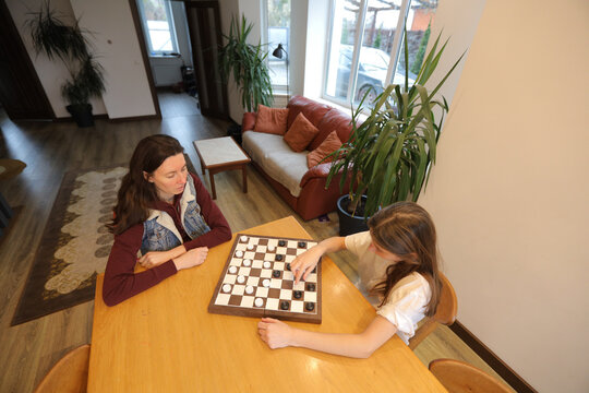Family game time: mother and daughter playing checkers at home
